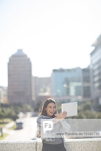 Glückliche junge Frau  die mit einem digitalen Tablett ein Selfie macht
