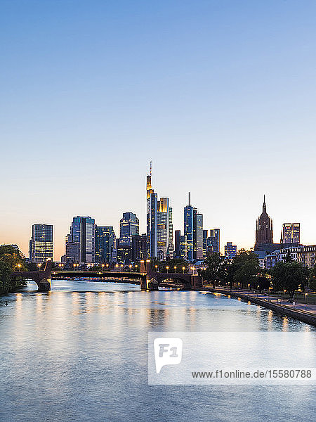 Szenische Ansicht eines Flusses in einer beleuchteten Stadt bei klarem Himmel während des Sonnenuntergangs in Frankfurt  Deutschland
