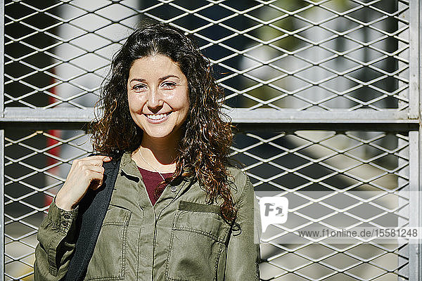 Portrait of smiling young woman at a fence