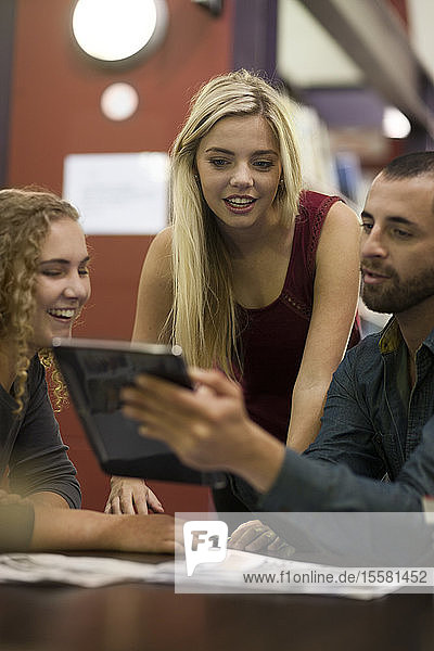 Studenten in einer Bibliothek mit digitalem Tablett