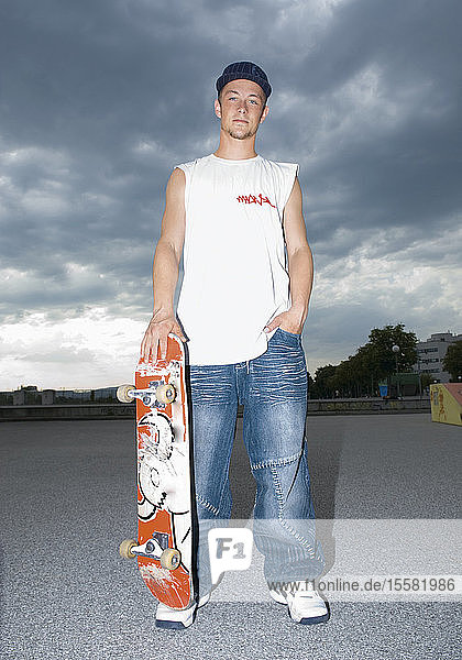 Österreich  Junger Mann mit Skateboard  Porträt