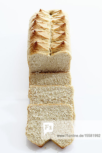 Laib Weißbrot mit Scheibe auf weißem Hintergrund