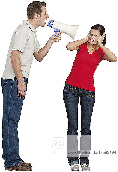Mid adult man with megaphone shouting on young woman