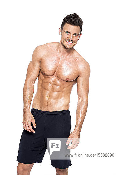 Porträt eines lächelnden  muskulösen Mannes ohne Hemd vor weißem Hintergrund
