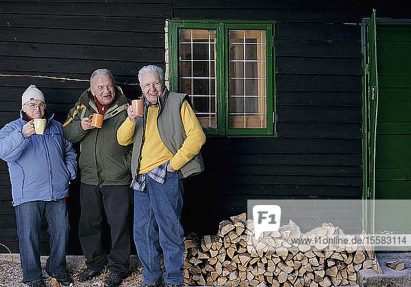 Deutschland  Ältere Männer stehen vor einem Blockhaus