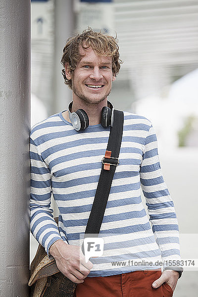 Portrait of smiling man with headphones and shoulder bag