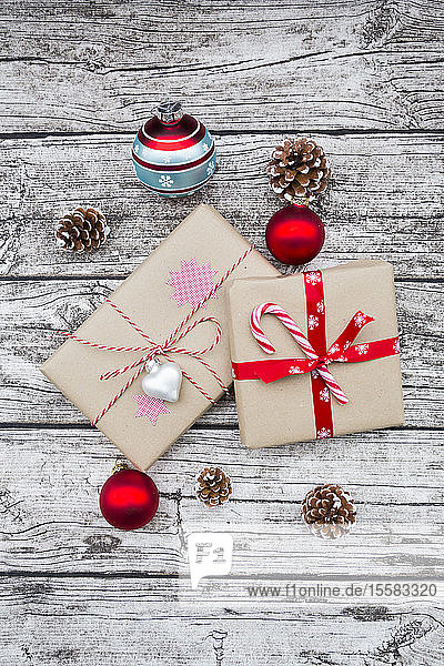 Eingepackte Weihnachtsgeschenke Weihnachtskugeln und Tannenzapfen auf Holz