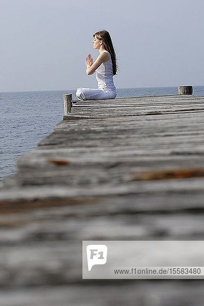 Italien  Gardasee  Frau (20-25) übt Yoga auf einem Steg