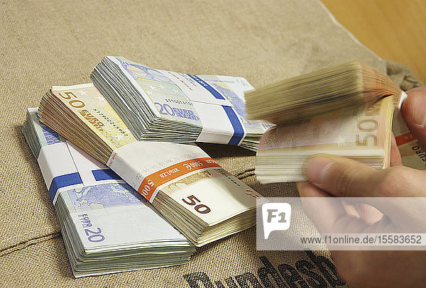 Person blättert durch Bündel von Euro-Banknoten