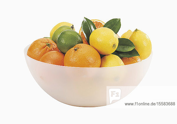 Schale mit frischen Orangen und Zitronen auf weißem Hintergrund
