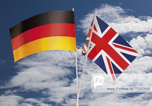 Englische Flagge und deutsche Flagge gegen bewölkten Himmel