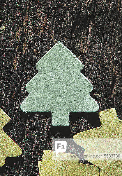 Farbiges Papier in Form eines Tannenbaums auf dunklem Holz