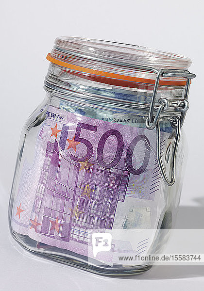 Nahaufnahme von Euro-Banknoten in einem luftdichten Glasgefäss vor weissem Hintergrund