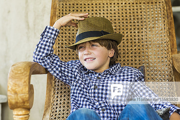Porträt eines sechsjährigen Jungen auf einem Korbstuhl sitzend