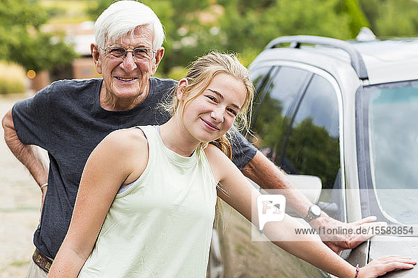Älterer Mann  Großvater und seine 13-jährige Enkelin waschen gemeinsam ein Auto in der Einfahrt