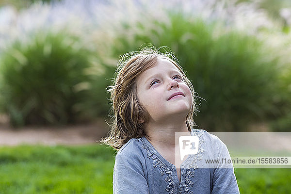 5 year old boy relaxing on lush green lawn looking up
