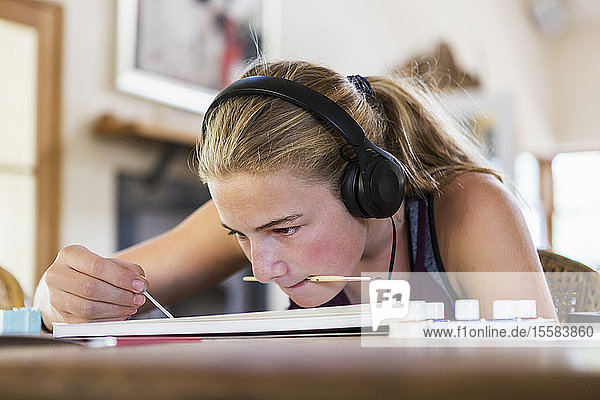 13-jähriges Mädchen zu Hause trägt Kopfhörer beim Malen