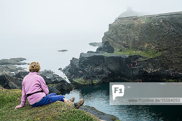 Frau  die auf einer Klippe an der Küste von Pembrokeshire  Wales  Großbritannien  sitzt.