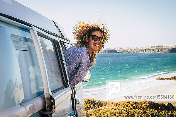 Lächelnde Frau lehnt sich aus dem Wohnmobil am Strand von Fuerteventura  Kanarische Inseln