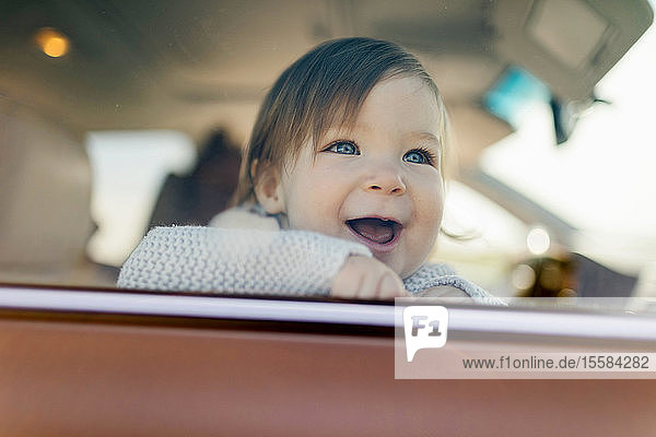 Smiling baby girl behind car window