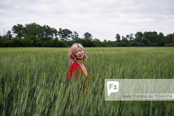 Frau mit rosa Haaren in einem Weizenfeld