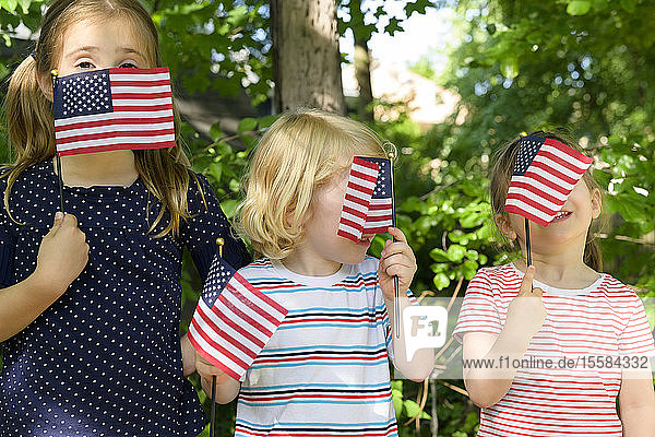 Children holding American flags over their faces