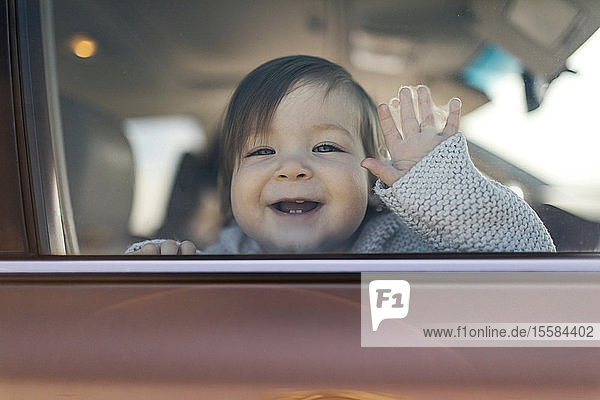 Smiling baby girl behind car window
