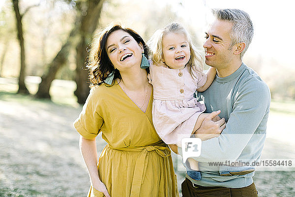 Smiling parents holding their daughter in park