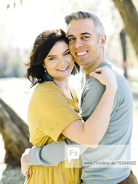 Lächelndes erwachsenes Paar  das sich im Park umarmt