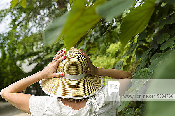 Woman wearing straw hat by trees