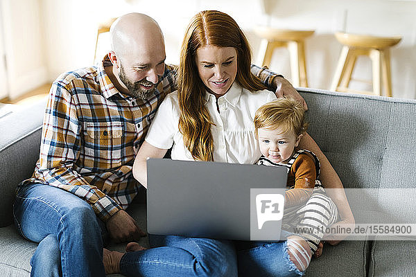 Family using laptop on sofa