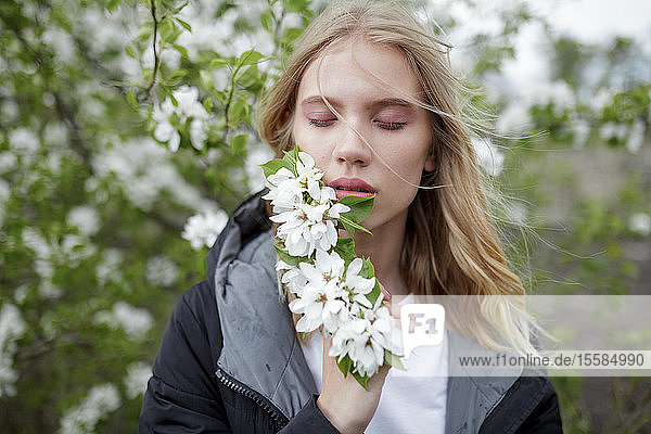 Junge Frau mit geschlossenen Augen hält weiße Blüten