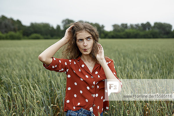 Frau macht Gesicht im Weizenfeld