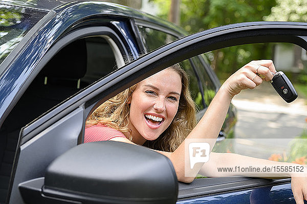 Smiling young woman in car holding car keys