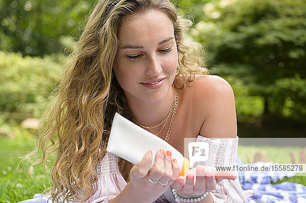 Young woman holding sun cream in garden