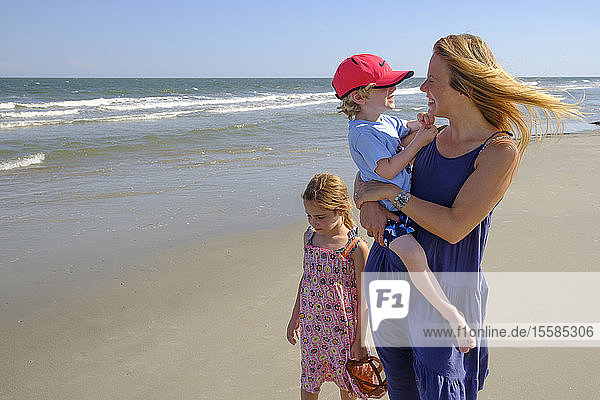 Mutter und Kinder gehen am Strand spazieren