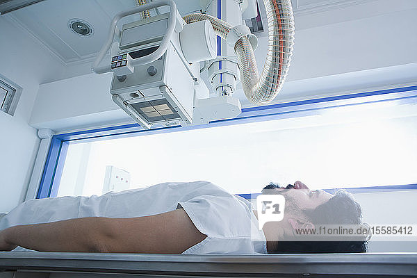 Junger männlicher Patient mit einem CT-Scan in der radiologischen Abteilung Seitenansicht