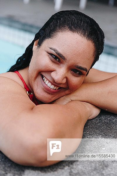 Mittelgroße erwachsene Frau mit nassem Haar  die am Swimmingpool im Freien lehnt  Kopf- und Schulterporträt  Kapstadt  Südafrika