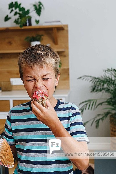 Boy biting into cupcake at home