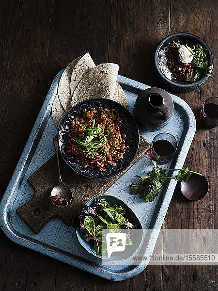 Rustic low key still life with tray of chilli con carne salad and coffee overhead view