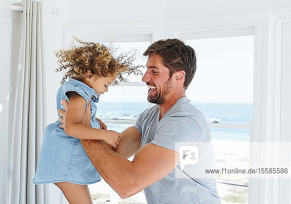 Vater spielt und schaukelt Tochter im Strandhaus