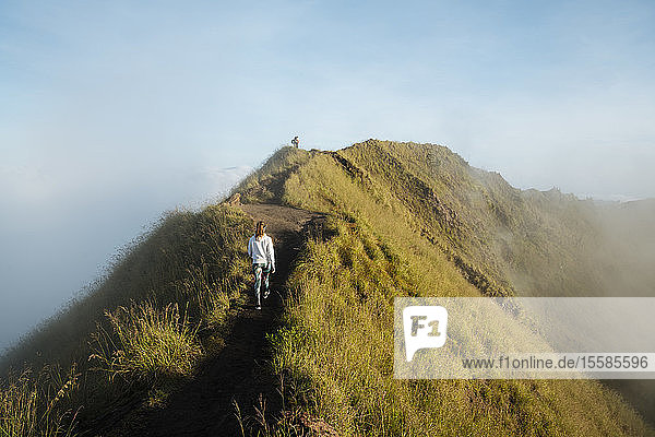 Young female tourist hiking on top of misty mountain  rear view  Bali  Indonesia