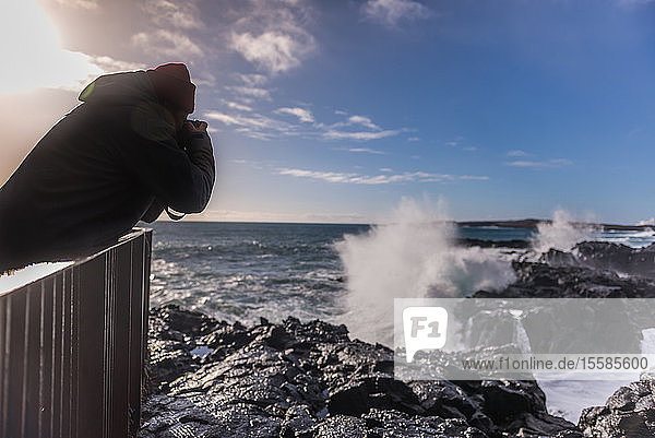 Tourist fotografiert Meereswellen vom Pier aus  Reykjanes  Island