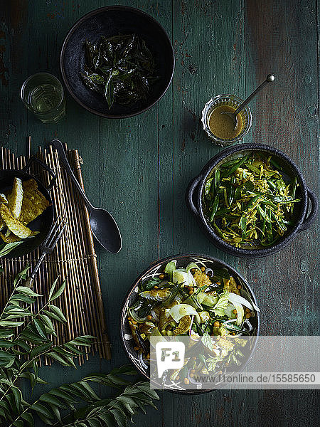 Rustic low key still life with bowls of curry leaf fish salad and green bean thoran on table overhead view