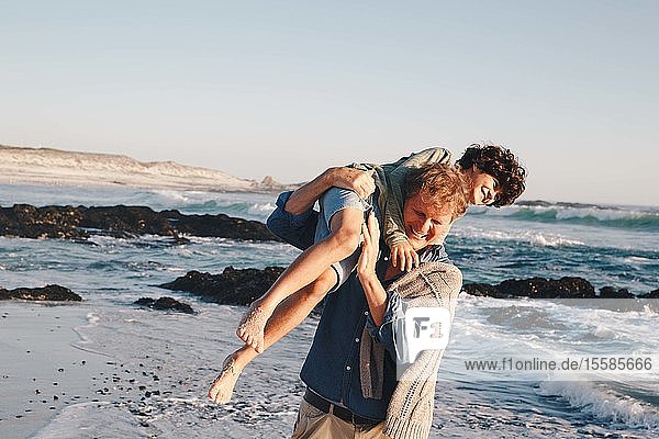 Vater trägt Sohn am Strand über die Schulter