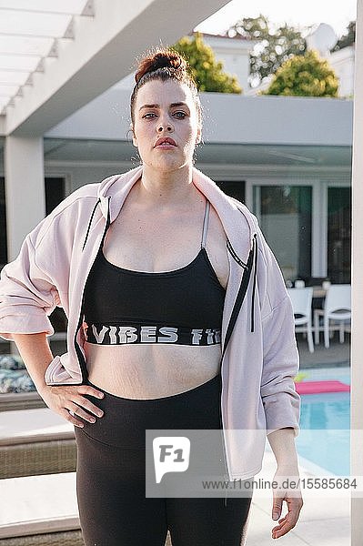 Woman in workout attire posing at swimming pool