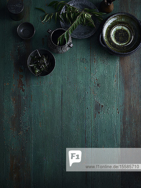 Rustikales Low-Key-Stillleben mit Schalen und Tasse auf grünem Holztisch  Draufsicht