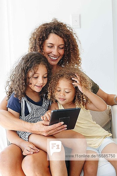 Mother and daughters using digital tablet at home