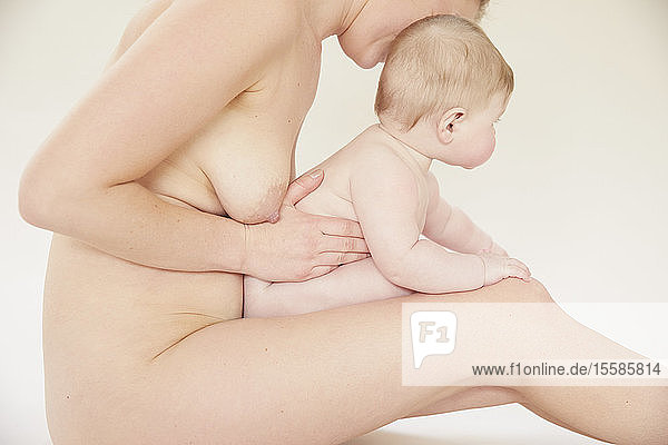 Nackte Mutter bindet mit nacktem Baby auf dem Schoß