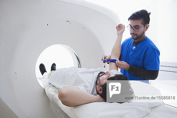 Junger männlicher Radiologe der einen männlichen Patienten auf die CT-Untersuchung in der radiologischen Abteilung vorbereitet